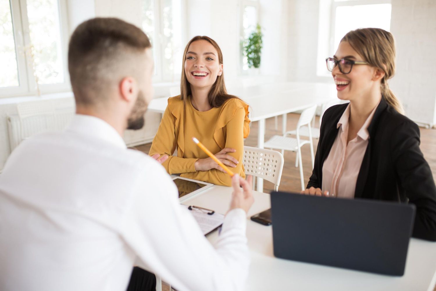 two beautiful business women happily talking with male applicant work young smiling employers spending job interview modern office
